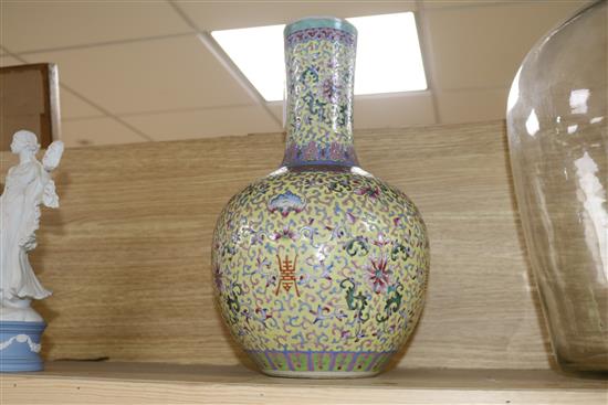 A Canton enamelled bottle vase, decorated flowers, foliate scrolls and Chinese characters on a yellow ground, height 40cm, faults